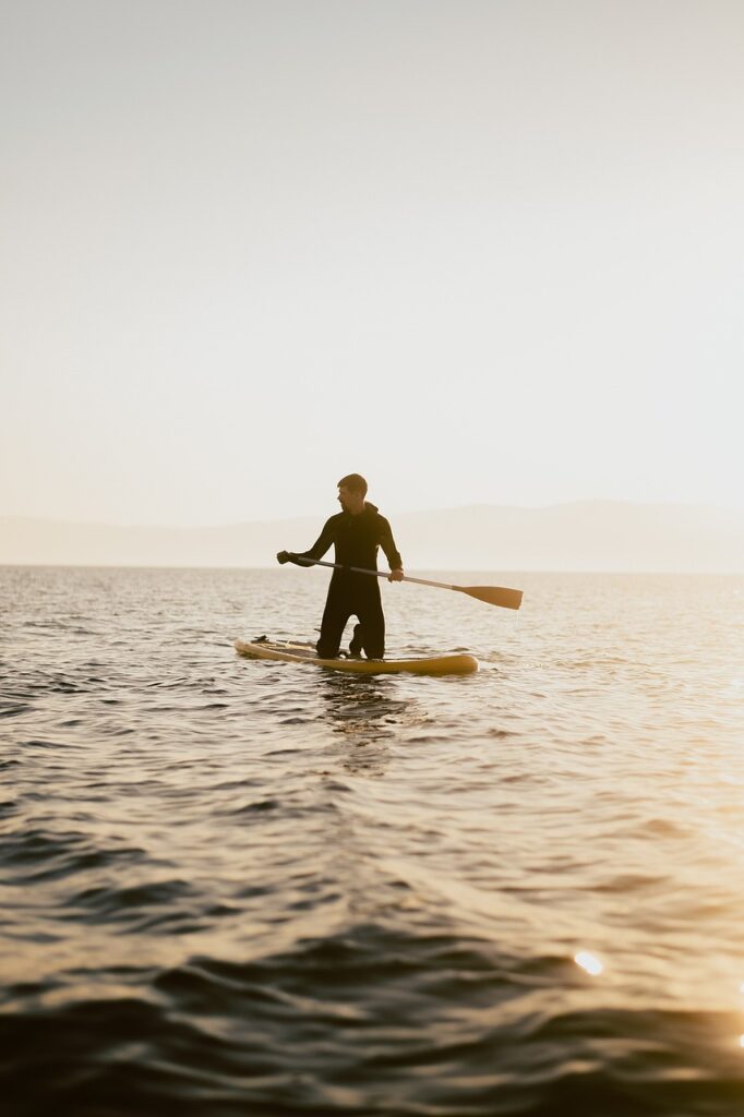 "Homme à genoux sur un paddle, pagayant sur la mer calme